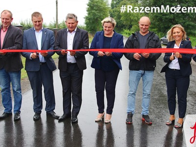 Zdjęcie przedstawia samorządowców przecinających czerwoną wstęgę na wyremontowanym odcinku drogi