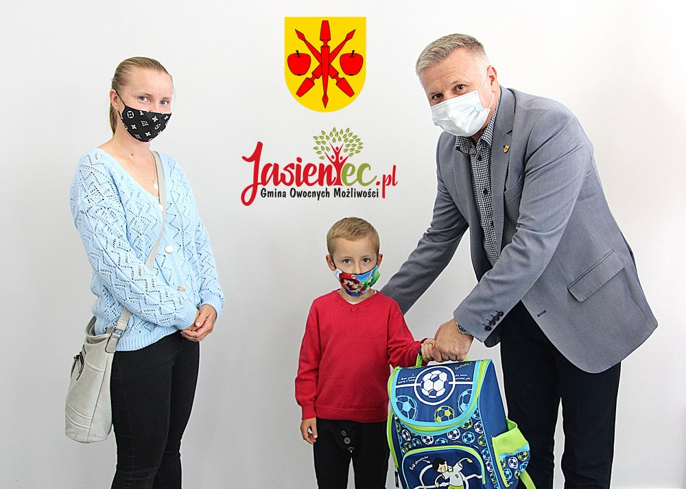Zdjęcie przedstawia sekretarza Tomasza Podhoreckiego wręczającego Wojtkowi zestaw szkolny 