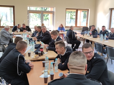 Zdjęcie ze spotkania OSP, przy stołach siedzący strażacy