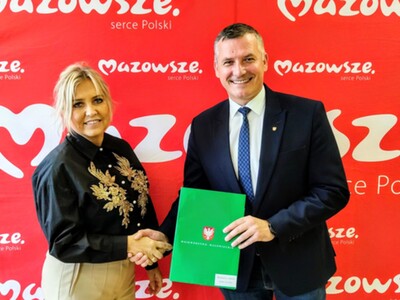 Na zdjęciu ososby trzymające teczke z umową