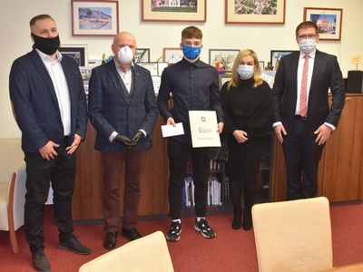 Łukasz Chudziński z pamiątkowym listem gratulacyjnym w dłoni u boku Przewodniczącego Rady Miejskiej w Sulęcinie Zbigniewa Szczepańskiego, Burmistrza Sulęcina Dariusza Ejcharta, swojej mamy oraz trenera.