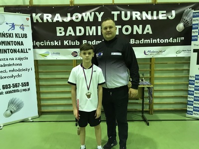 Zdjęcie przedstawia trenera wraz z zawodnikiem podczas Krajowego Turnieju Badmintona.