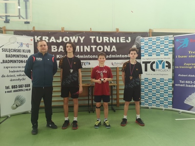 Trener klubu wraz z trzema zawodnikami, uczestnikami klubu odznaczonymi medalami. Jeden z zawodników trzyma w ręce statuetkę.