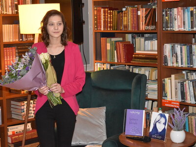 Wieczór autorski poezji Angeliki Daukszy z Sulęcina.
Angelika z kwiatami na tle książek. 