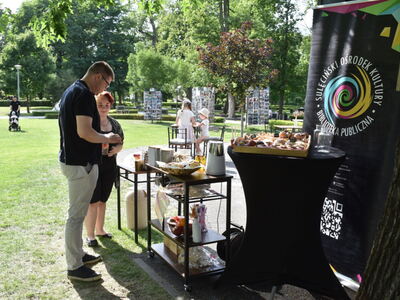 Kulturalny relaks w Parku Miejskim. Burmistrz Sulęcina z mieszkanką Gminy Sulęcin stojący przy stoliku z poczęstunkiem. 