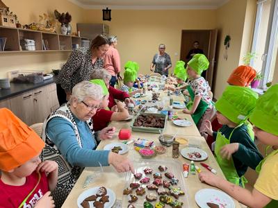 Alt="Zjęcie przedstawia międzypokoleniowe pieczenie pierników przedszkolaków z Przedszkola Samorządowego w Sierakowie Śląskim oraz Seniorów z  Dziennego Domu SENIOR + w Panoszowie."