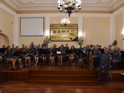 Alt="Zdjęcie przedstawia Gminną Orkiestrę Dętą podczas koncertu w Państwowej Szkole Muzycznej im. Janiny Garści w Lublińcu."