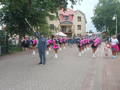 Alt="Zdjęcie przedstawia występ Gminnej Orkiestry Dętej z Ciasnej wraz z Zespołem Tańca Mażoretkowego "Copacabana" podczas XIII Ogólnopolskiego Przeglądu Paradnych Orkiestr Dętych w Rowach."