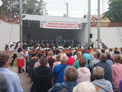 Alt="Zdjęcie przedstawia występ Gminnej Orkiestry Dętej z Ciasnej podczas XIII Ogólnopolskiego Przeglądu Paradnych Orkiestr Dętych w Rowach."