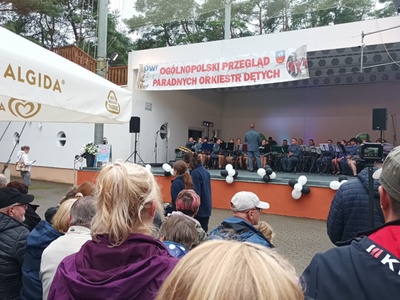 Alt="Zdjęcie przedstawia występ Gminnej Orkiestry Dętej z Ciasnej podczas XIII Ogólnopolskiego Przeglądu Paradnych Orkiestr Dętych w Rowach."
