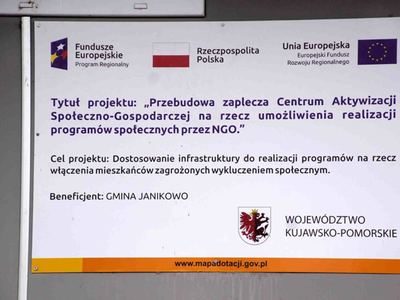 Biała tablica z czarnymi napisami i 2 kolorowymi logami na której znajduje kolorowe Logo Urzędu Marszałkowskiego Województwa Kujawsko Pomorskiego i Logo Gminy Janikowo oraz informacja Projekt Przebudowa zaplecza centrum aktywizacji społeczno gospodarczej na rzecz umożliwienia realizacji programów społecznych przez NGO [400x300]