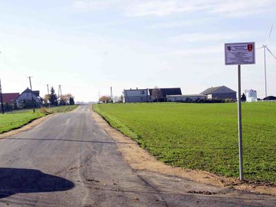 Zdjęcie na którym widać drogę asfaltową śródpolną prowadzącą pomiędzy gospodarstwami rolnymi a polami [400x300]