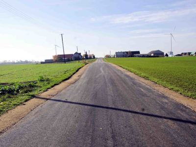 Zdjęcie na którym widać drogę asfaltową śródpolną prowadzącą pomiędzy gospodarstwami rolnymi a polami [400x300]