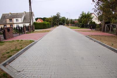 Zdjęcia przedstawiają drogę między domami oraz terenami zielonymi.