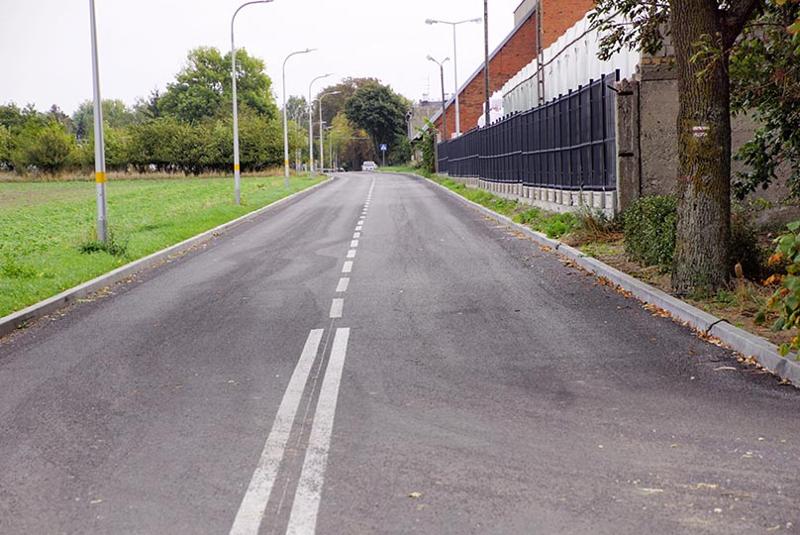Zdjęcia przedstawiają drogę między domami oraz terenami zielonymi.