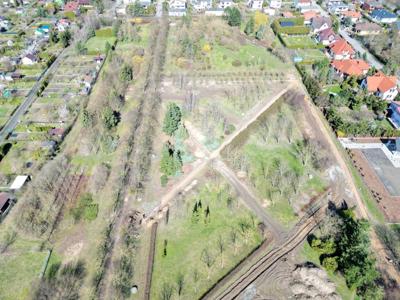 Zdjęcia z lotu ptaka przy przedstawiają park z rozpoczętymi pracami przy użyciu koparki. Na zdjęciach widać trawniki alejki drzewa i krzewy.