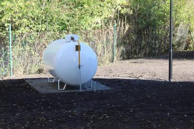 Biały zbiornik na gaz ustawiony na betownowych płytach.