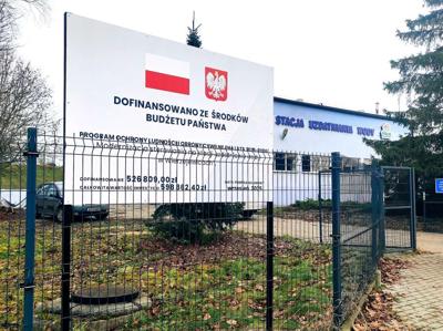 Tablica informacyjna dotycząca finansowania inwestycji, w tle widać budynek SUW