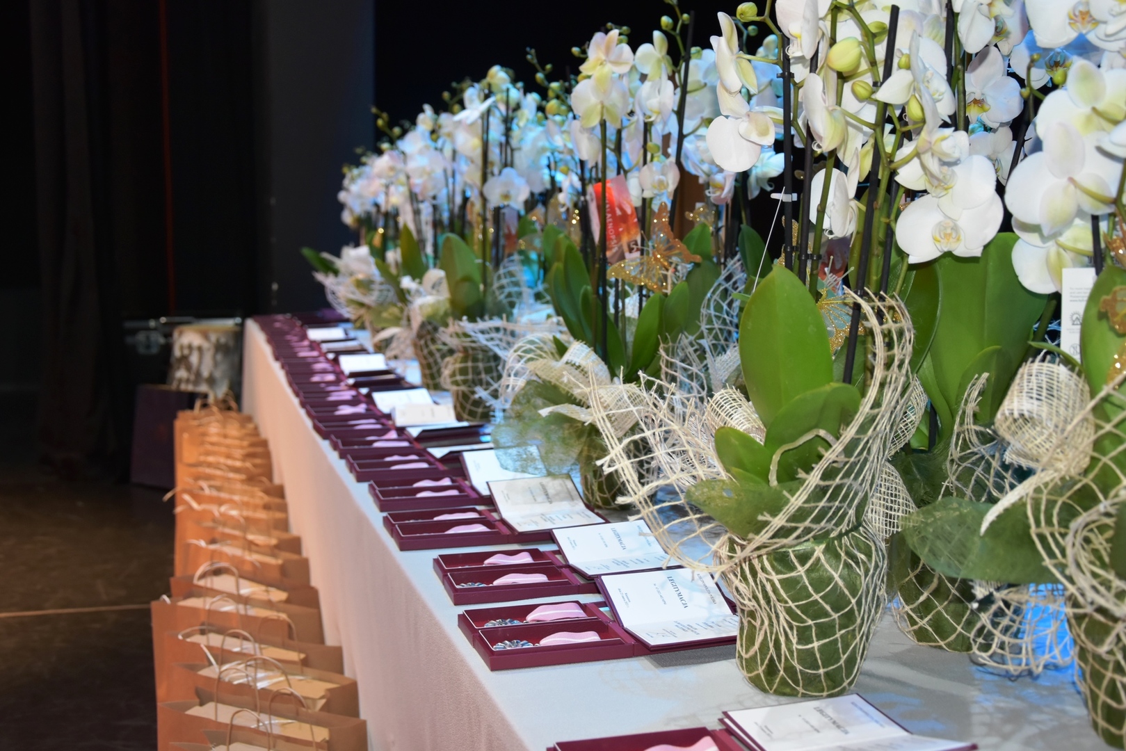 Medale Róży dla Jubilatów Złotych Godów leżące na stole obok białych storczyków