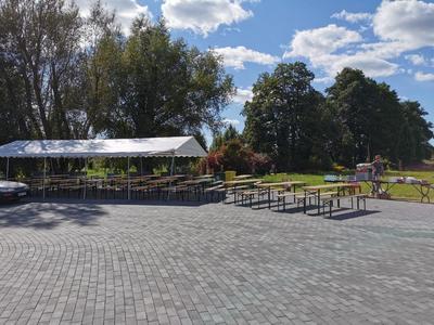 stoły i ławy piknikowe pod namiotem na tle drzew