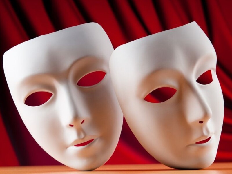 Zdjęcie przedstawia dwie białe maski teatralne na czerwonym tle