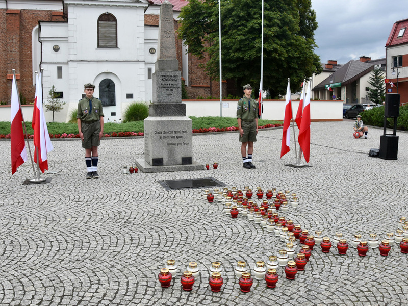 Zdjęcie przedstawia tarczyński rynek, pomnik oraz kotwicę ułożoną ze zniczy