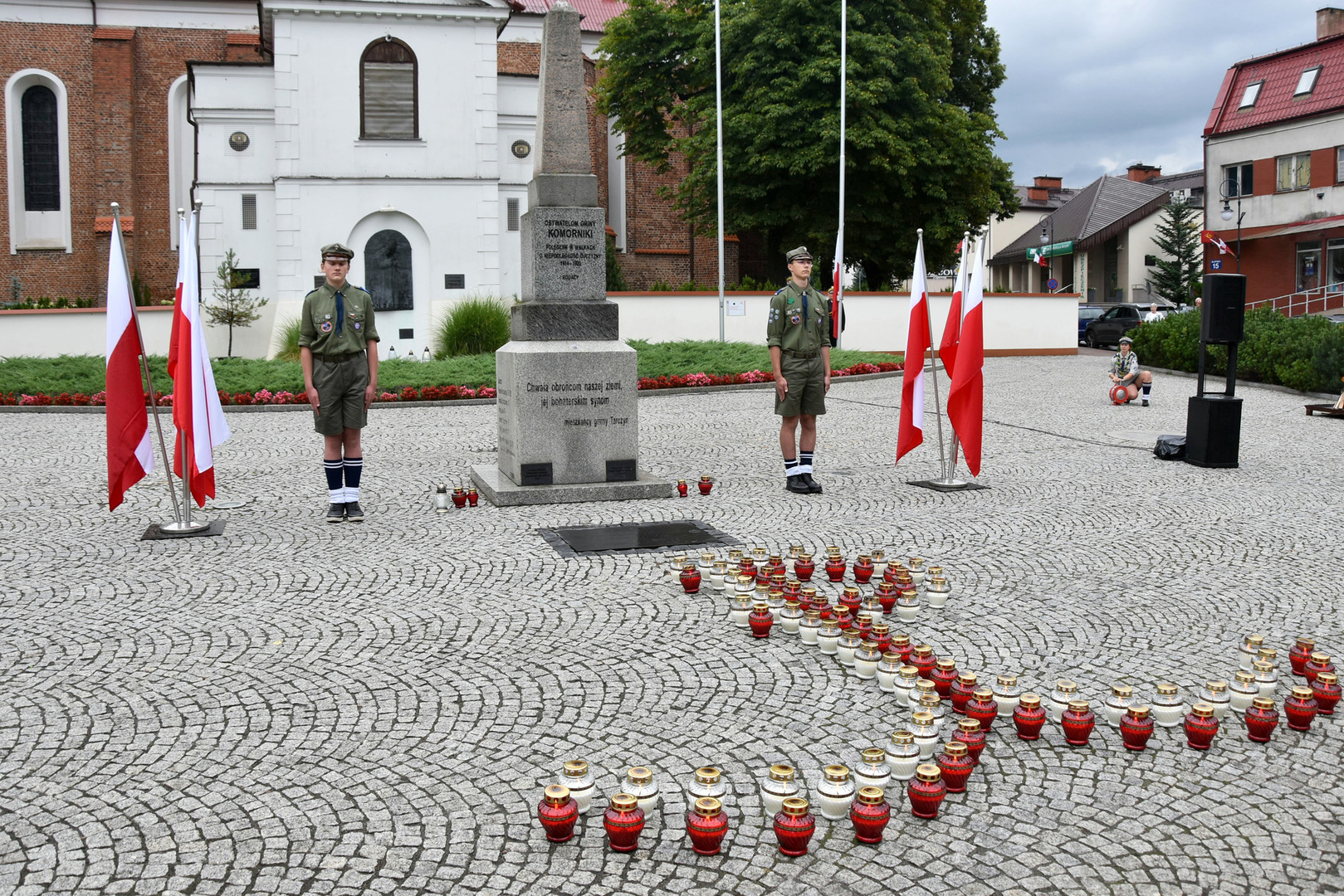 Zdjęcie przedstawia tarczyński rynek, pomnik oraz kotwicę ułożoną ze zniczy