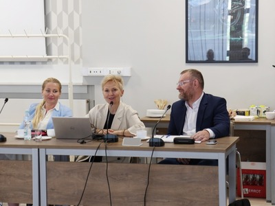 Zdjęcie przedstawia trzy osoby siedzące przy stole