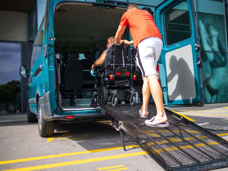 Zdjęcie przedstawia osobę na wózku wjeżdżającą do busa transportującego