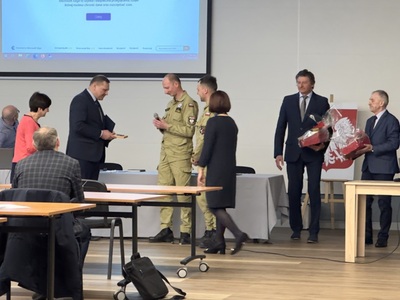 Burmistrz wraz ze strażakami podczas wręczania upominku