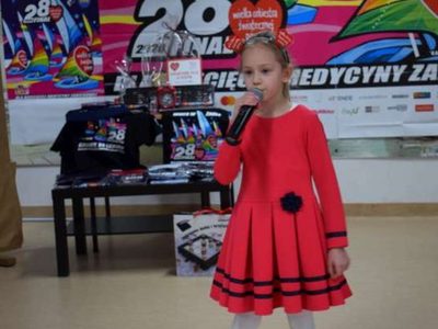 Zdjęcie przedstawia dziewczynkę śpiewającą na scenie