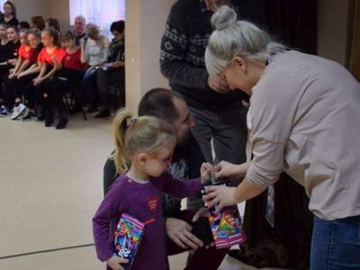 Zdjęcie przedstawia dziewczynkę wrzucającą pieniądze do puszki WOŚP 
