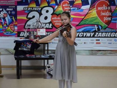 Zdjęcie przedstawia dziewczynkę grającą na instrumencie 