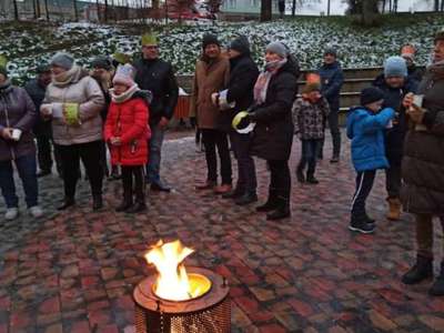 Zdjęcie przedstawia ludzi zebranych wokół ogniska