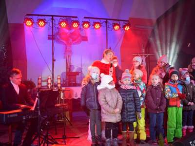 Wokalistka oraz dzieci śpiewając na scenie