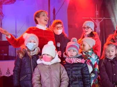 Wokalistka oraz dzieci śpiewając na scenie