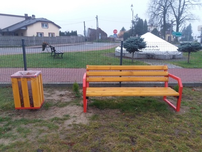 Ławka oraz kosz na śmieci na placu zabaw.