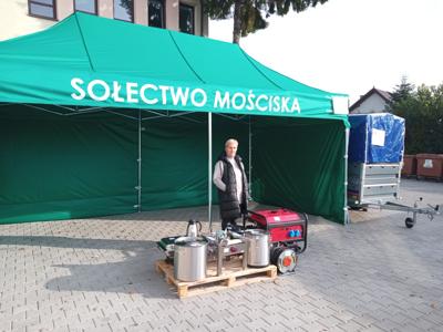 Sołtys wsi Mościska stojąca pod namiotem, na pierwszym planie zakupiony sprzęt