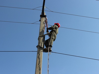Elektryk dokonujący naprawy na słupie elektrycznym