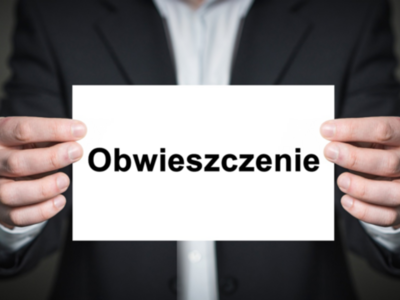Mężczyzna w garniturze trzymający kartkę z napisem: "Obwieszczenie"