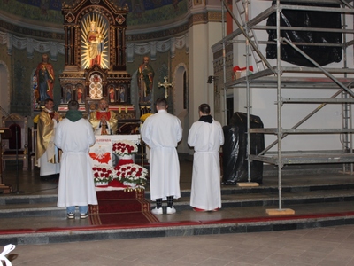 Na zdjęciu widoczny ołtarz przybrany w białoczerwone barwy oraz kapłani odprawiający liturgię.