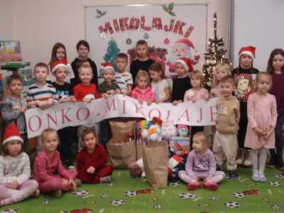 Grupa dzieci pozująca do zdjęcia z napisem ONKO-MIKOŁAJE. Wewnątrz.