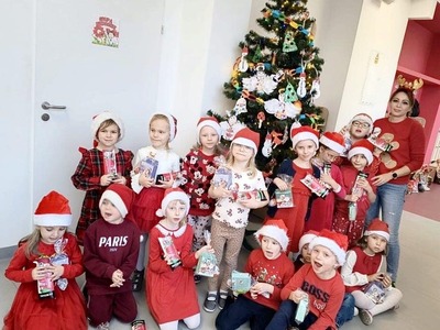 Grupa przedszkolaków z opiekunką pozująca do zdjęcia. Wewnątrz.