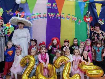 Grupa dzieci i trzy panie w strojach karnawałowych pozują do zdjęcia. Wewnątrz.