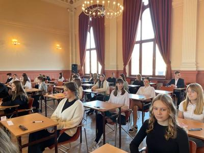 Grupa uczniów siedząca na sali. Wewnątrz.