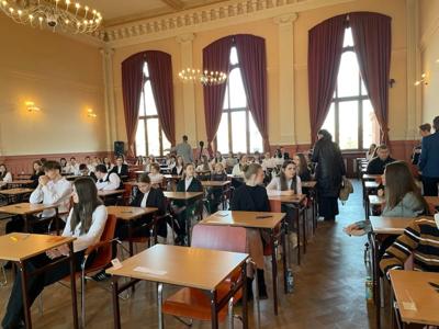 Grupa uczniów siedząca na sali. Wewnątrz.