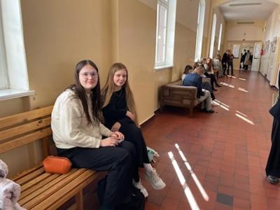 Dwie uczennice siedzące na korytarzu. Wewnątrz.