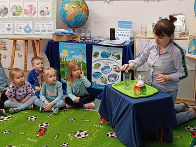 Grupa dzieci i pani podczas zabawy. Wewnątrz.