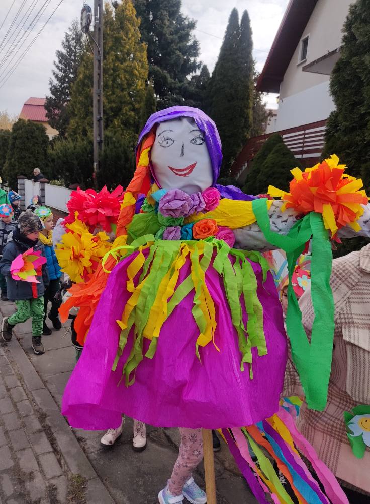 Kukła Marzanny, w tle widać dzieci. Na zewnątrz.