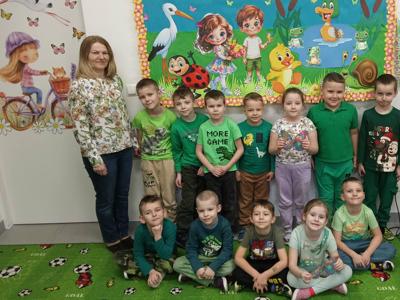Grupa dzieci i pani pozujący do zdjęcia. Wewnątrz.